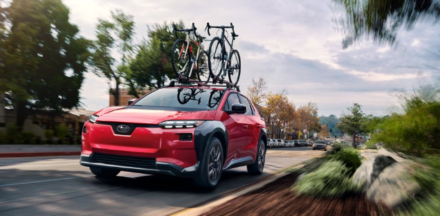 Unlimited A red Solterra Premium drives up a small town road with two bikes loaded on top.
