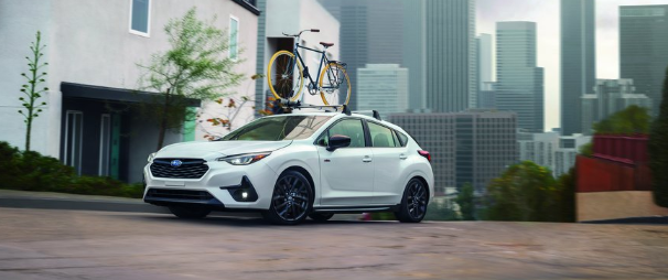Unlimited Impreza RS with bike rack and bike driving on wet road, cityscape in background