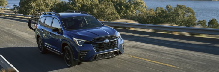blue subaru ascent driving down a road